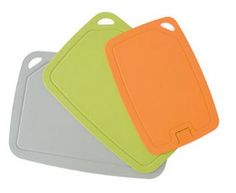 three different colored cutting boards sitting next to each other on a white surface with an orange, green, and gray tag