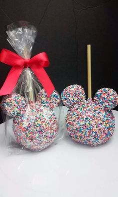 two mickey mouse shaped lollipops in plastic bags with a red bow on top