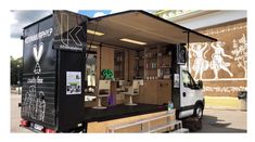 a food truck is parked in front of a building with its doors open and it's interior painted black