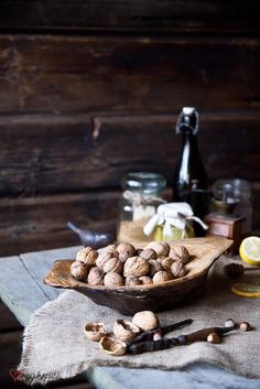 nuts in a wooden bowl on a table with honey and lemons next to it