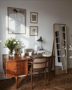 a wooden desk sitting next to a mirror on top of a hard wood floor covered in furniture