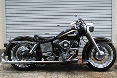 a black motorcycle is parked in front of a garage door with roller doors behind it