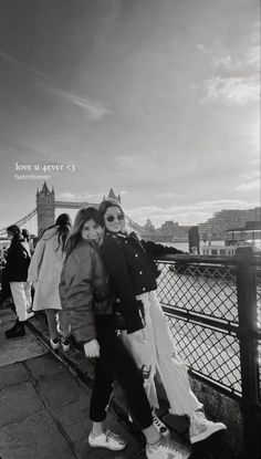 two women standing next to each other on a bridge