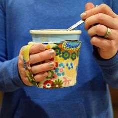 a woman holding a cup with a spoon in it