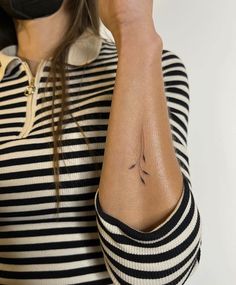 a woman with a tattoo on her arm holding a cell phone up to her ear