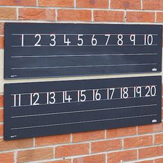 two signs on the side of a brick building with numbers and times printed on them