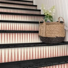 a basket sitting on top of a set of stairs next to a vase with flowers