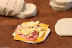 bread with ham and cheese on it sitting on a wooden table next to other food items