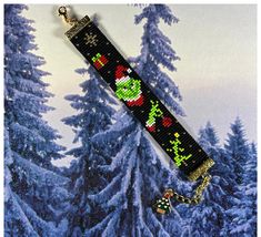 a christmas bracelet with an ornament on it in front of snow covered trees