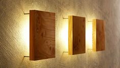 three wooden blocks are mounted to the wall, one is lit up and the other is turned on