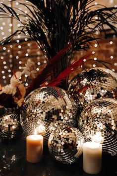 disco balls and candles on a table in front of a christmas tree with white lights