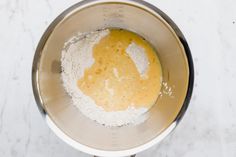 a metal bowl filled with dry ingredients on top of a white counter