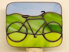 a green and yellow glass night light with a bicycle on it