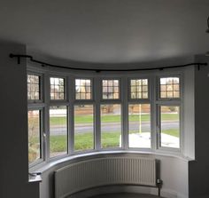 an empty room with three windows and a circular window in the center, looking out onto a street