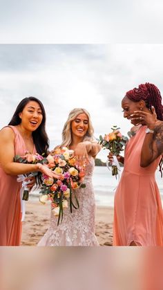 three bridesmaids on the beach with their bouquets in front of them and one woman covering her mouth