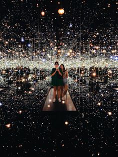 two people standing on a platform in front of a large display of lights and bubbles