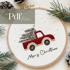 a cross stitch christmas ornament with a red truck carrying a tree