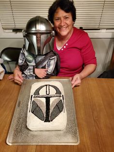 a woman sitting at a table with a cake in front of her that has a helmet on it