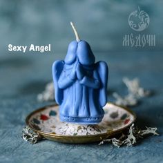 a blue candle sitting on top of a saucer next to a plate with an angel