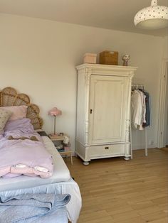 a bedroom with white furniture and pink bedding