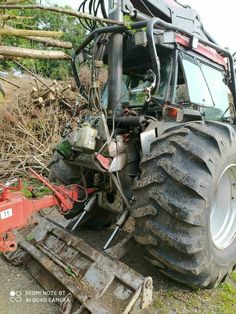 a large tractor is parked next to a pile of branches