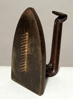 an old iron sitting on top of a white table next to a brown object with gold lines