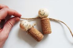 two corks with faces drawn on them are being held by someone's hand