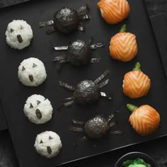 halloween treats are arranged in the shape of pumpkins and ghost faces on a black tray