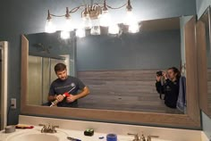 a man standing in front of a bathroom mirror