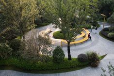 an aerial view of a park with benches, trees and people walking on the path