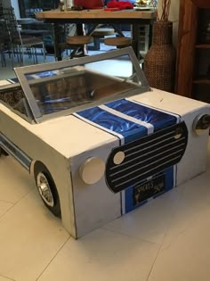 a cardboard box shaped like a car with a glass window and blue ribbon on the front