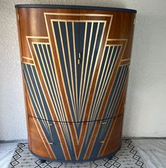 an art deco cabinet with wood and blue paint on the front, sitting on a tiled floor