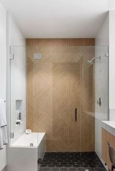 a bathroom with a walk in shower next to a white sink and wooden wall behind it