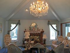 a living room filled with lots of furniture and a chandelier hanging from the ceiling