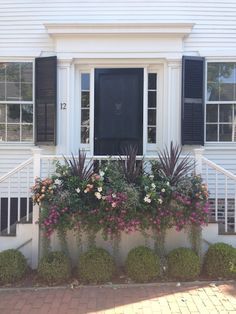 a white house with black shutters and flower boxes