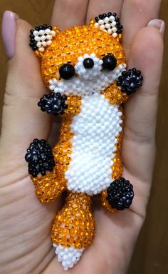 a hand holding a small beaded fox brooch