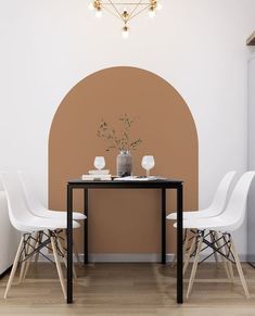 two white chairs and a black table in front of a brown wall with an arch