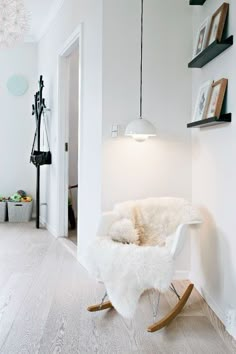 a white chair sitting on top of a hard wood floor next to a wall mounted light