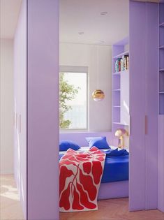 a bedroom with purple walls and blue bedding, bookshelf in the background