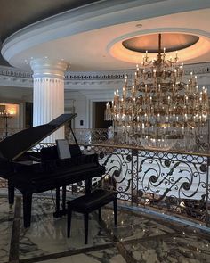 a grand piano sits in front of a chandelier