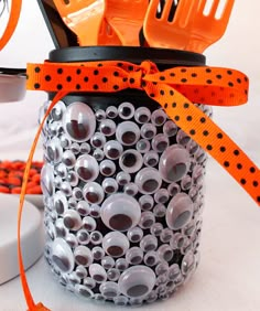 an orange ribbon is tied around a jar filled with halloween candies and sprinkles