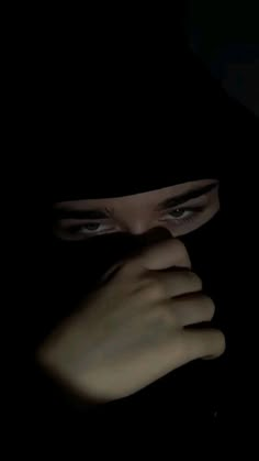 a woman's face is shown in the dark with her hands covering her face