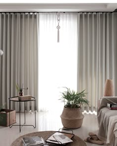 a living room filled with furniture and a large window covered in drapes next to a plant