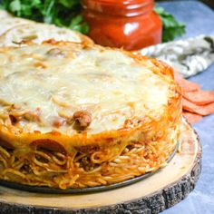 a pizza covered in cheese and sauce on top of a wooden platter next to vegetables