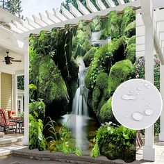 an outdoor shower curtain with a waterfall and green plants on the outside, in front of a house