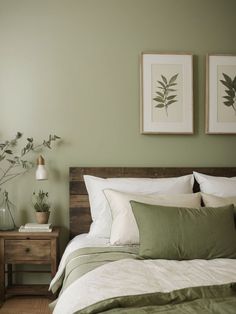 a bedroom with green walls and white bedding, two framed pictures on the wall