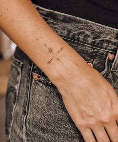 a woman's arm with a small cross tattoo on the left side of her wrist