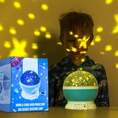 a young boy standing next to a blue and white light projector with stars on it