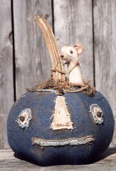 a stuffed mouse sitting on top of a blue pumpkin with holes in the bottom and sides