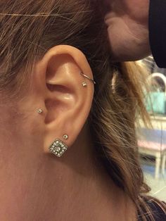 a close up of a person's ear with two piercings on it and one behind the ear